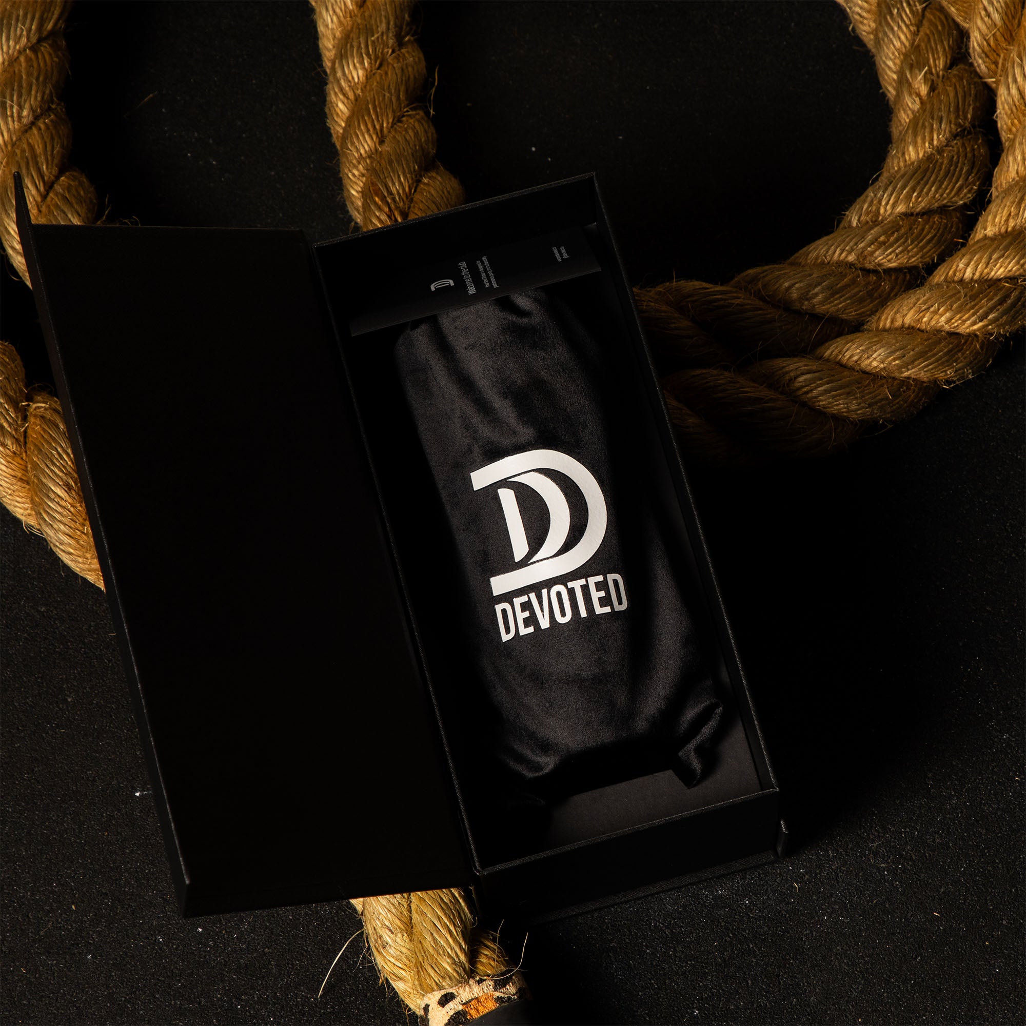 Black 'Devoted' velvet bag in a black box, laid on a gym rope premium gym shaker